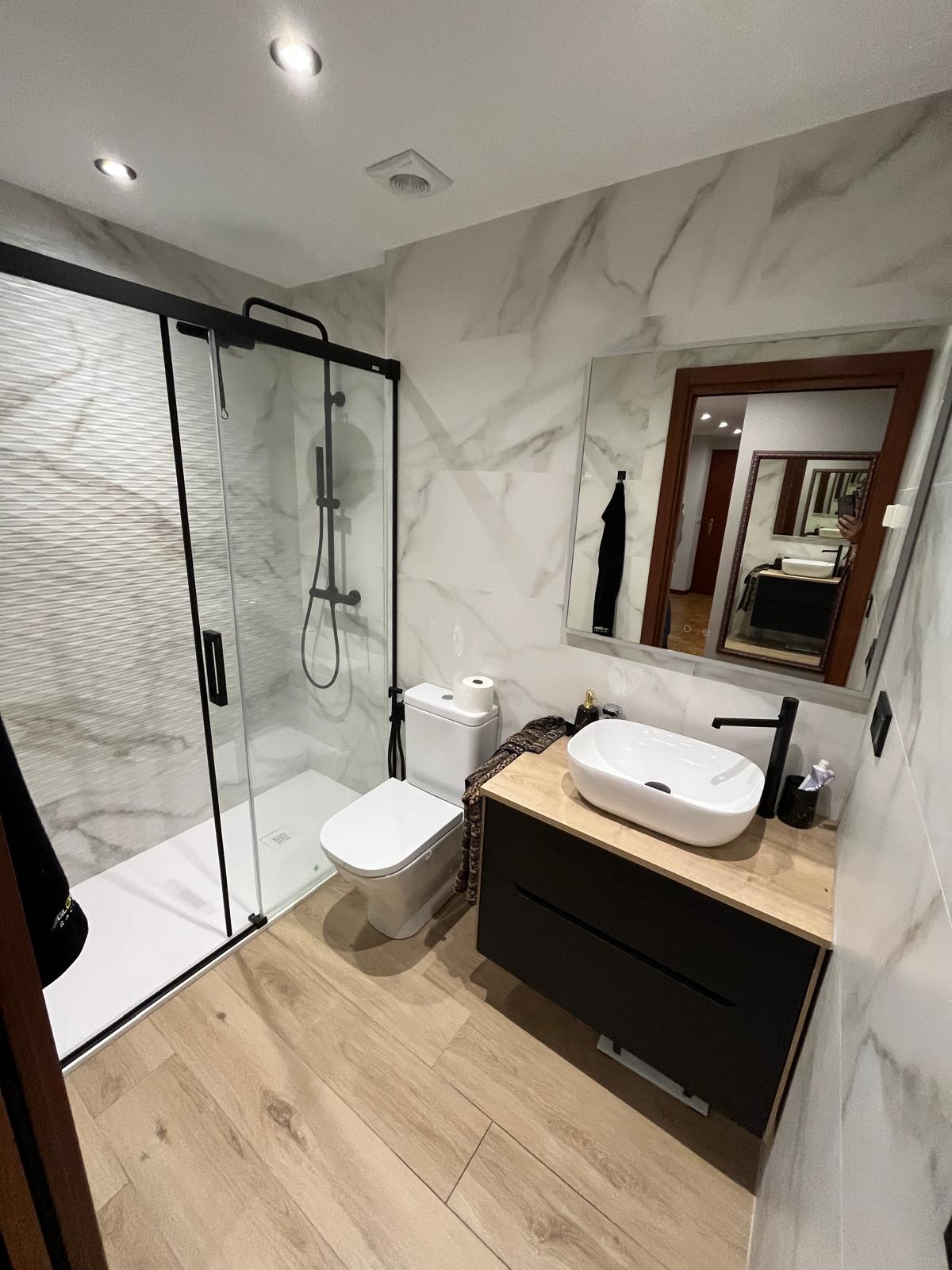 Baño de lujo con mampara de cristal y acabados en madera